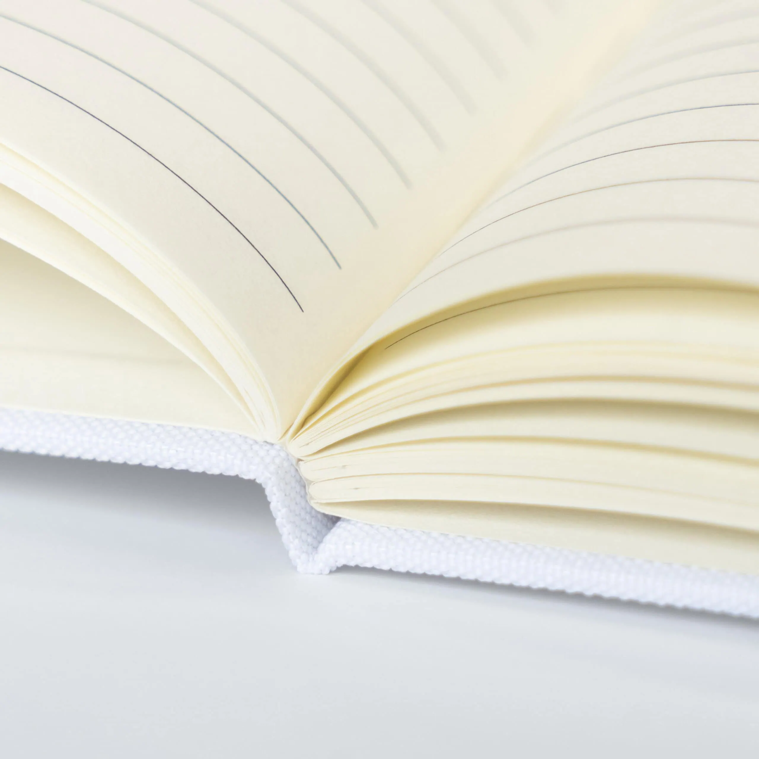 Folha de caderno ou livro aberto com páginas de papel creme, focada na escrita e leitura.
