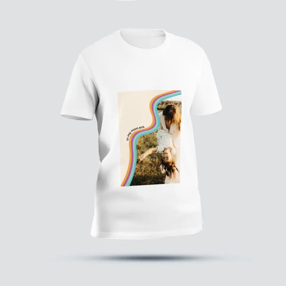 TShirtMomEra 1. Camiseta branca com estampa de uma criança sorridente ao ar livre, com cores vibrantes e o texto "In my mom era".