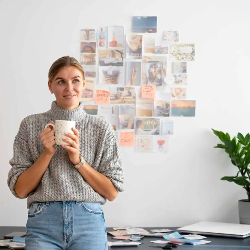 1. Mulher segura chá, fundo com colagem de fotos e post-its, ambiente de trabalho criativo.